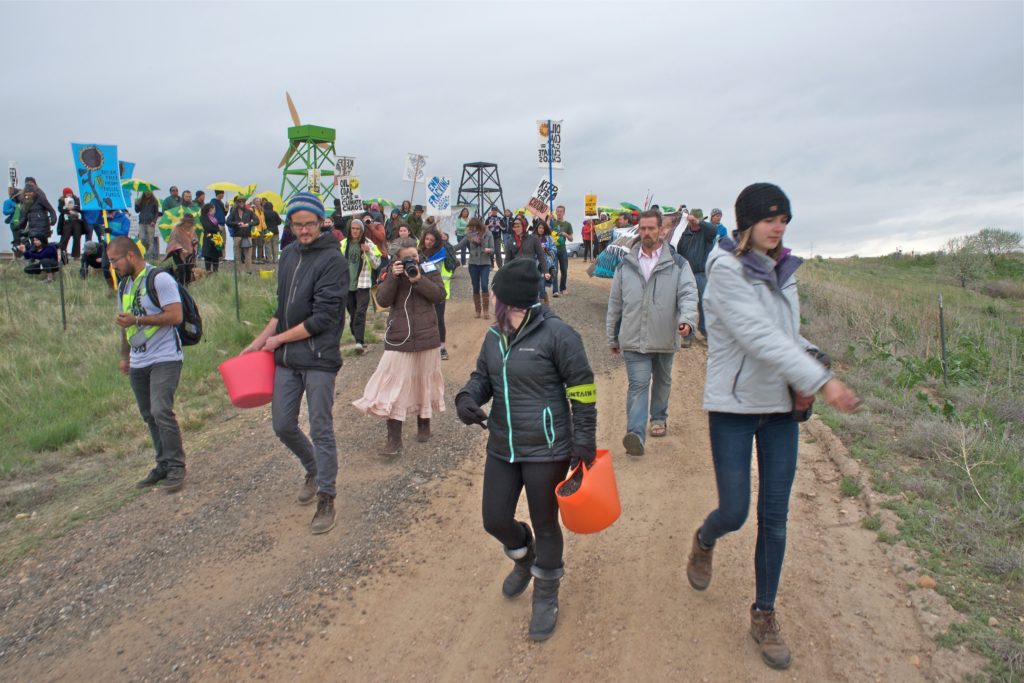 Protestors willing to be arrested throw seeds as they make their way past police toward the well site.