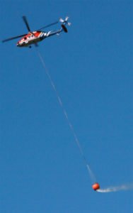 A helicopter takes water from Barker Reservoir to combat the flames.