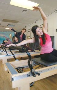 from front to back: Michelle Garcia, Tamara Conner (with instructor Tracy Bodden) and Laura Adams enjoying a workout at Center Stream Pilates.  