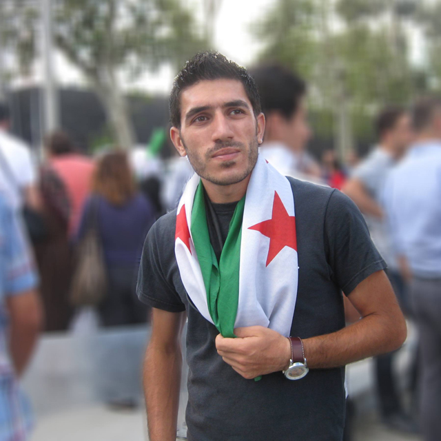 CU graduate student Salam proudly wears a Syrian flag at a demonstration in Turkey in 2013. 