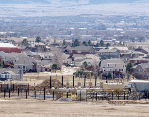Hold on to your hats, it seems good government is possible fracking oil and gas well fenced in suburban neighborhood with trees and mountains in the background. Erie Colorado