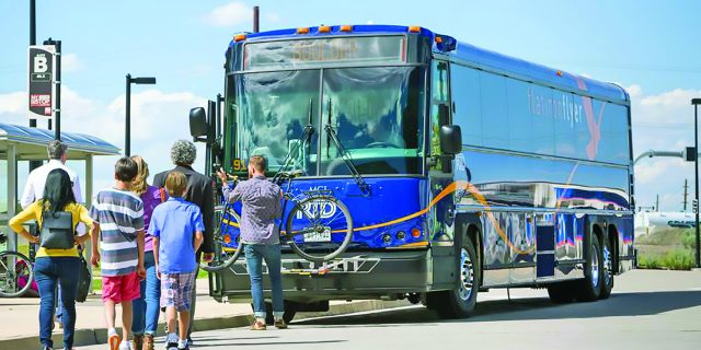 Front of blue Flatiron Flyer bus with bike in rack and passengers waiting to board RTD route from Denver to Boulder